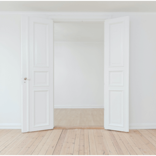 Ein heller, weißer Innenraum mit geöffneter Flügeltür zu weiterem Zimmer